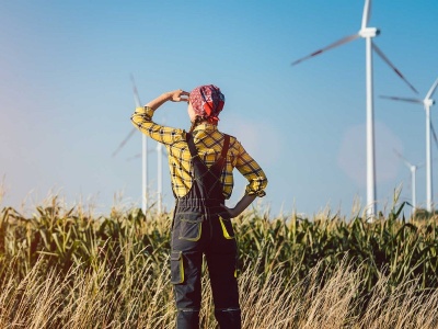 Eine Frau blickt auf Windräder zur Erzeugung von Windenergie und deren Vor- und Nachteile für die Zukunft.