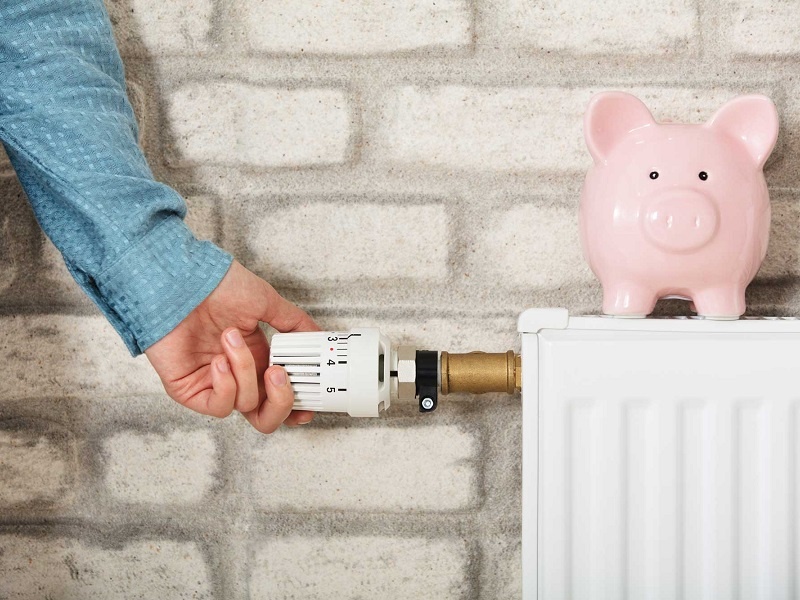 Mann reduziert am Thermostat die Wärme, um Gas zu sparen und einen Gasmangel zu vermeiden.